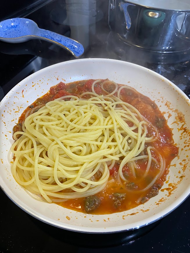 Pasta being added to pasta lla putanesca.